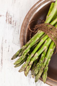 Fresh asparagus bundle isolated on wooden background. Healthy vegetable concept.