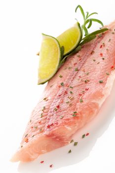 Frozen fish fillet with fresh herbs, lime and spices isolated on white background. Culinary seafood eating.