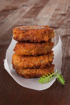 Falafel patty pile on wooden background with fresh arugula herb. Culinary vegan eating.