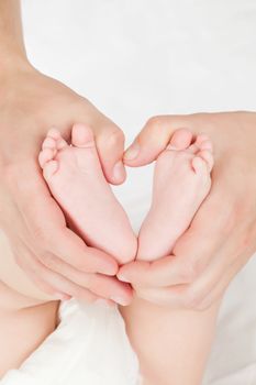 Female caucasian hands holing little baby feet on white background. Security, safety, protection parenting mother and baby concept.