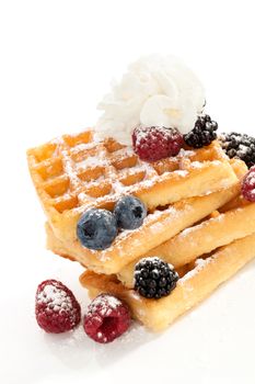 Delicious waffle with blackberries, raspberries and blueberries and cream isolated on white background. Culinary sweet food.