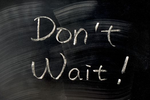 Don't Wait - words written with chalk on a blackboard