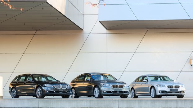 MUNICH, GERMANY - DECEMBER 27, 2013: New entire model line of powerful BMW 535 family and business classes. Three wet after rain cars - the full series: station wagon, sedan, liftback.
