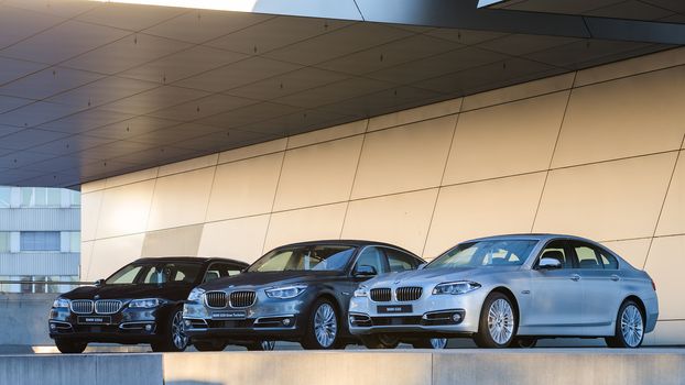 MUNICH, GERMANY - DECEMBER 27, 2013: New collection of powerful BMW 535 business and family classes. Three wet after rain cars - the entire model line: sedan, liftback, station wagon.