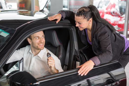 Saleswoman in car dealership selling a automobile