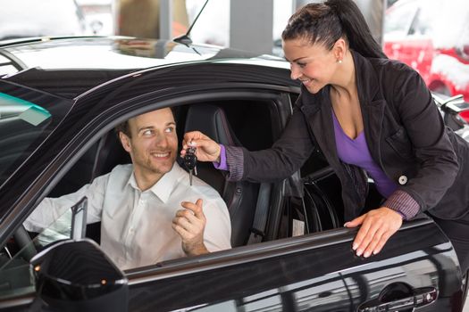 Saleswoman in car dealership selling a automobile