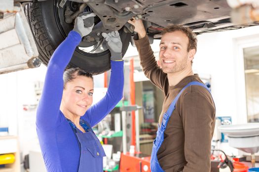 Two mechanics repairing or inspecting a car on hydraulic lift