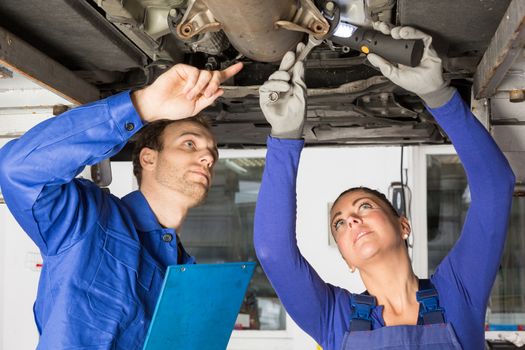 Car mechanics repairing a car on hydraulic lift