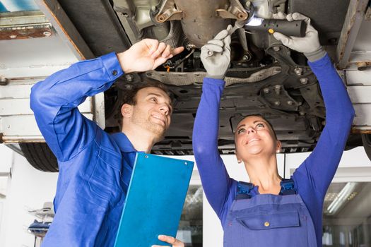 Car mechanics repairing a car on hydraulic lift