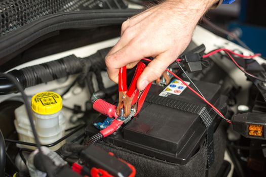 Mechatronic technician working on the battery of a car