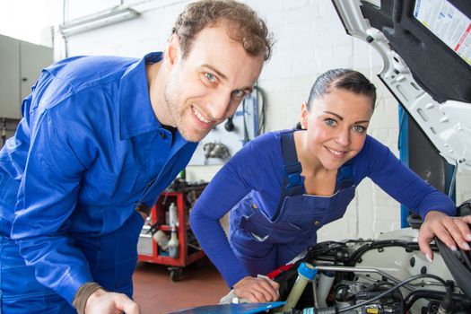 Two mechanics repairing a car in a garage or workshop