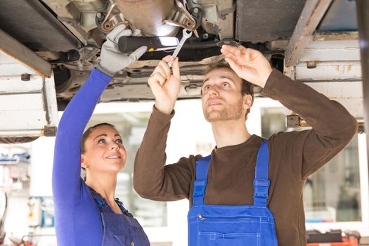 Two mechanics repairing or inspecting a car on hydraulic lift