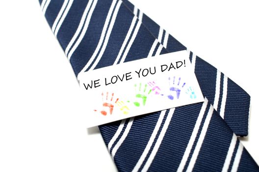 We love you dad with colorful hand prints tag on blue tie over white background