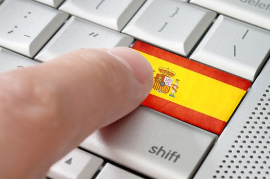 Business concept male finger pressing Spain enter key on metallic keyboard