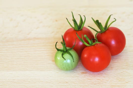 Four cherry tomatoes on wooden cutting board