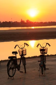 Silhouetted bicycles near Mekong river at sunset, Vientiane, Laos, Southeast Asia
