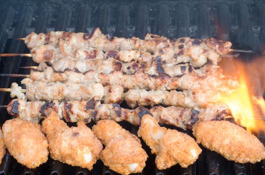 Porc skewers and chicken wings on grill