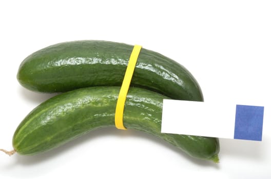 Two Fresh green cucumbers bond together by a yellow rubber band with a piece of sticky  note