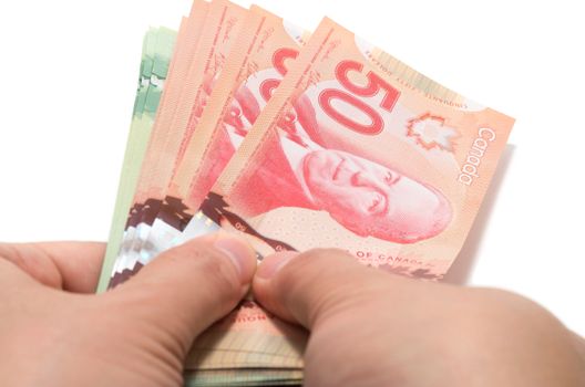 Hand holding a series of Canadian banknotes on white background