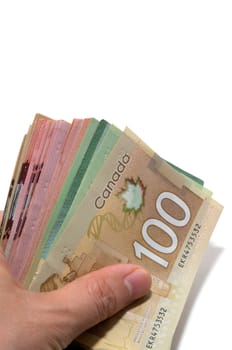 Hand holding a series of Canadian banknotes with 100 dollars on top