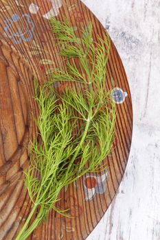 Fresh dill on wooden vintage plate, top view. Culinary aromatic herbs. 