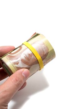 Hand holding a roll of 50 dollars Canadian with yellow plastic band over the eyes 