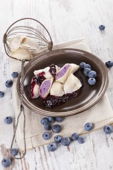 Delicious sweet dessert, rustic country style. Blueberry dumpling on plate on white wooden background. Culinary eating. 