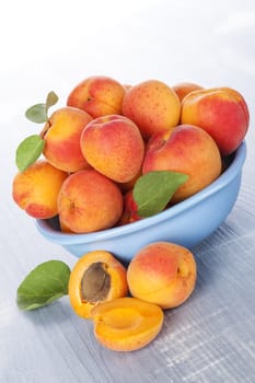 Apricots in blue bowl on blue wooden background. Delicious fresh fruit eating. 