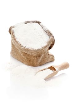 Flour in burlap sack and on wooden scoop. Bright baking background.