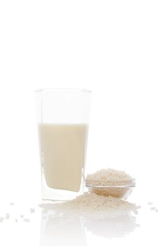 Rice milk in glass raw rice crop in bowl isolated on white background with reflection. Vegan eating.