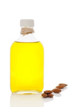 Organic almond oil in glass bottle and almonds isolated on white background with reflection. Healthy cooking and eating. 