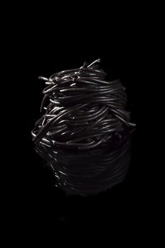 Black spaghetti isolated on black background. Culinary exquisite seafood pasta. Luxurious eating.