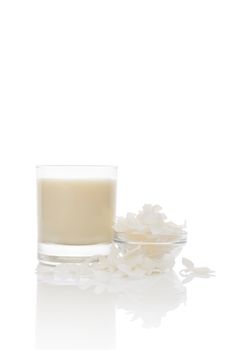 Coconut milk in glass, coconut flaked in bowl isolated on white background. Culinary healthy vegan and vegetarian eating.