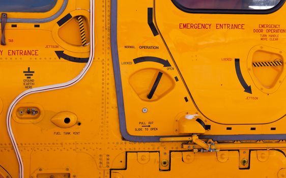 Background detail abstract of emergency handles, entrance hatches and exits on a yellow helicopter exterior