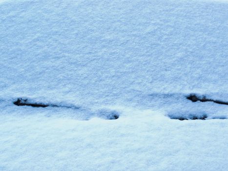 Background texture of a covering of pristine white fresh snow lying on vehicle windscreen on cold winter day