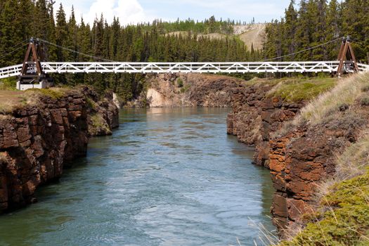 Miles Canyon Yukon River rock cliffs with suspension swing bridge just south of the city of Whitehorse Yukon Territory Canada