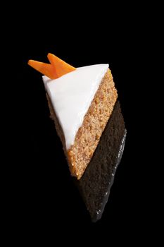 Delicious carrot cake piece isolated on black background. Luxurious sweet dessert.