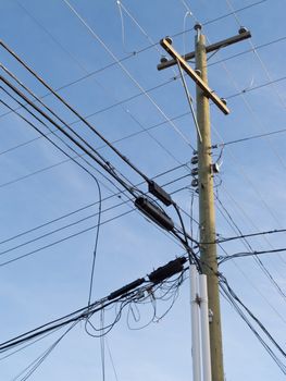 Utility pole hung with confusing and messed-up electricity power cables and telephone lines for residential supply