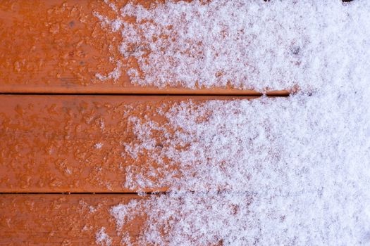 Winter nature background pattern abstract contrast of fresh snow melting on wet wooden deck plank surface