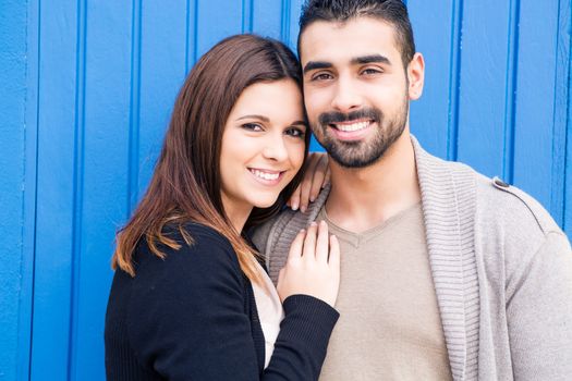 Young romantic couple hugging over blue background