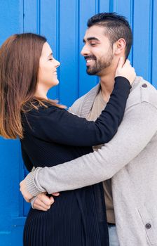 Young romantic couple hugging over blue background