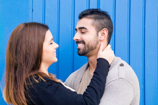 Young romantic couple hugging over blue background