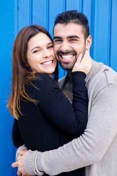 Young romantic couple hugging over blue background