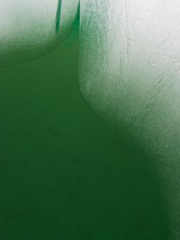 Underwater shot of melting iceberg in dark green water global warming abstract background