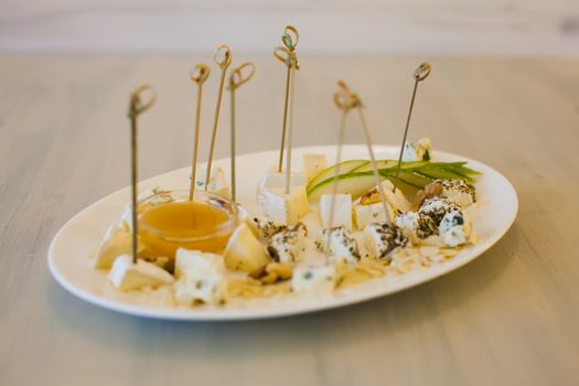 Plate with different types of cheese, honey, walnut and pear
