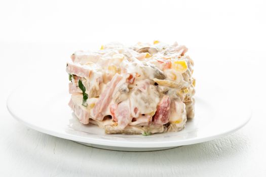 Portion of salad with ham, meat, mushrooms, vegetables and mayonnaise