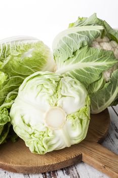 Fresh cabbage vegetable. Chinese cabbage, cabbage and cauliflower on wooden cutting board on white wooden background. Healthy organic seasonal vegetable.