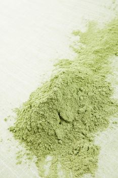 Green wheatgrass powder isolated on green background. Healthy green superfood. Alternative medicine.