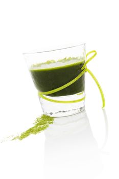Healthy living. Spirulina; chlorella and wheatgrass. Glass with green drink and wheatgrass ground isolated on white background. Food supplement.