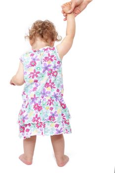 Babygirl in summer dress holding mothers hand and walking isolated on white background, back view. Learning to walk. 